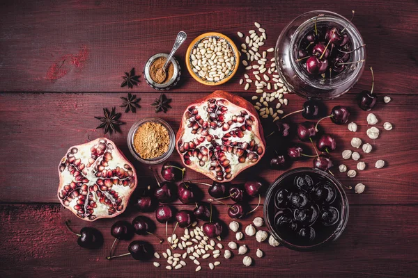 Still life with pomegranate , cherry and spices on the red wooden table. Concept of oriental fruits horizontal — Stock Photo, Image