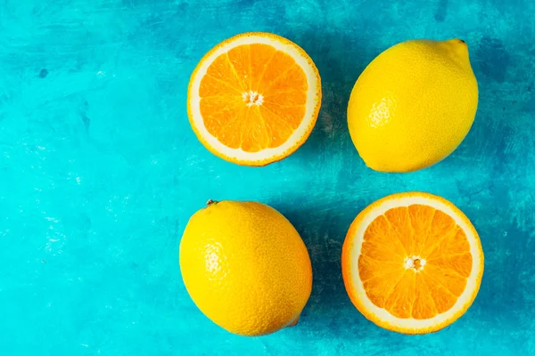 Citroenen en sinaasappelen aan de bovenkant van de cyaan achtergrond weergeven — Stockfoto