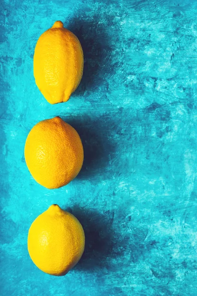 Желтые лимоны на голубом фоне вертикальные — стоковое фото