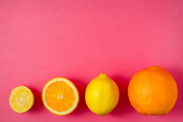 Lemons and oranges on the bright pink background