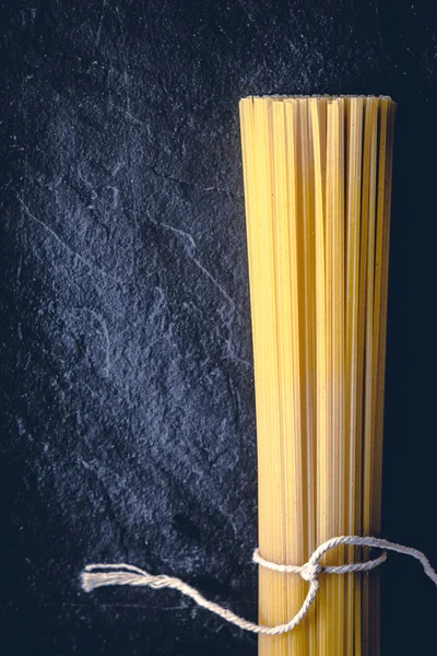 Raw spaghetti on the black stone background  vertical — Stock Photo, Image