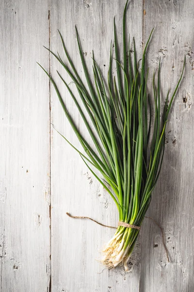 Zielonej cebuli na widok biały drewniany blat — Zdjęcie stockowe