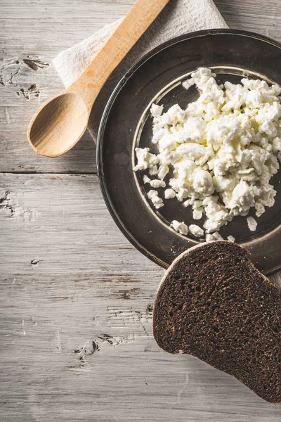 Fresh cottage cheese on the  metal plate  with bread on the white wooden table vertical — Stock Photo, Image