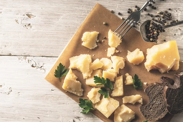 Ekmek, maydanoz ve karabiber Beyaz ahşap masa üstü görünümünde parşömen üzerine parmesan dilimlenmiş
