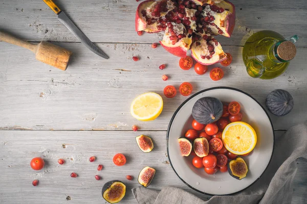 Granaatappel met vijgen en cherry tomaten op het witte houten tafelblad uitzicht — Stockfoto