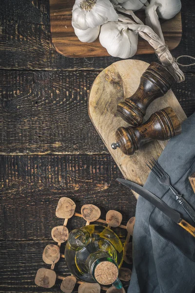 Σκόρδο, ελαιόλαδο και κουζίνα αξεσουάρ στο ξύλινο τραπέζι κάθετο — Φωτογραφία Αρχείου