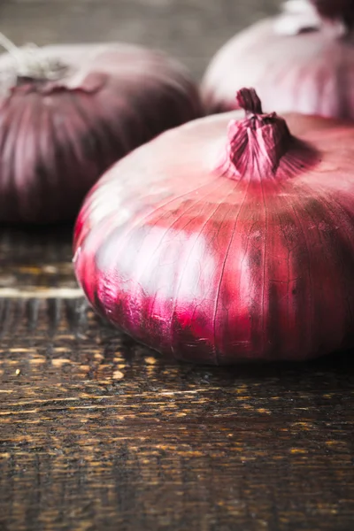 Dikey ahşap arka plan üzerinde kırmızı soğan — Stok fotoğraf
