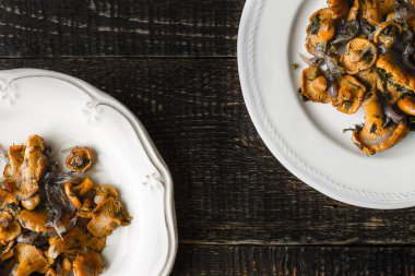 Eski ahşap masa üstüne seramik tabak kızarmış chanterelles görüntülemek