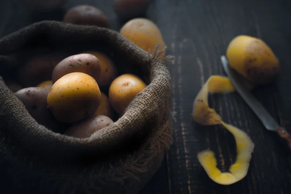 Pommes de terre dans le sac de toile sur la table en bois — Photo