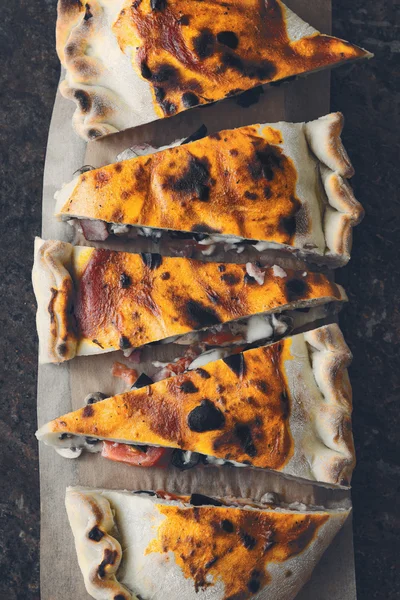 Sliced calzone on the stone background top view