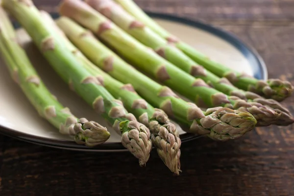 Asparagi su un piatto bianco sul tavolo di legno — Foto Stock