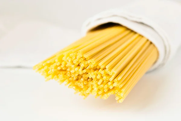 Raw pasta in a white towel on the white background — Stock Photo, Image
