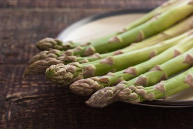 Ahşap masa üzerinde beyaz bir plaka üzerinde kuşkonmaz