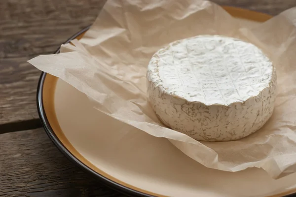 Whole camembert cheese on the white parchment — Stock Photo, Image