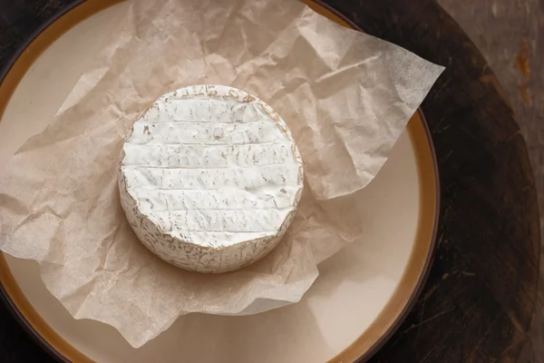 Whole camembert cheese on the white parchment — Stock Photo, Image