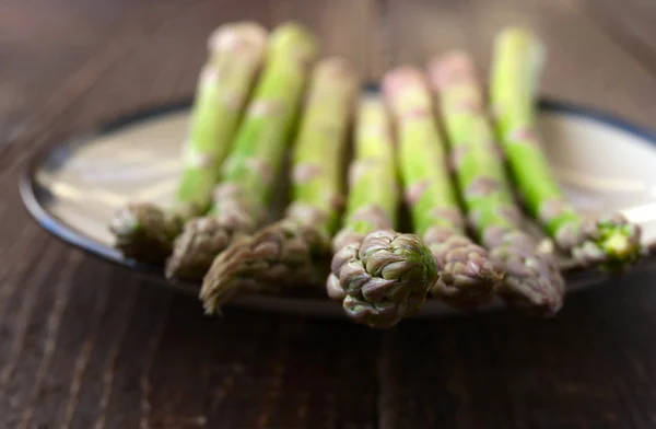 Asparagi su un piatto bianco sul tavolo di legno — Foto Stock