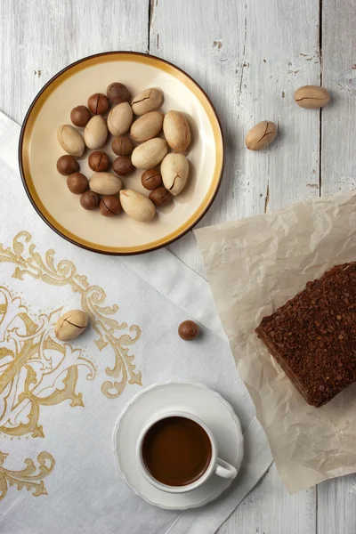 Un pastel de chocolate, una taza de café y nueces en el fondo blanco — Foto de Stock