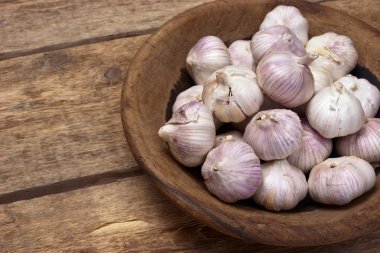 Ahşap arka plan üzerinde ahşap bir tabak içinde sarımsak