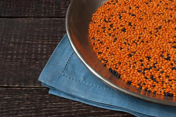 Vintage iron plate with red and black lentil on a blue napkin on — Stock Photo, Image