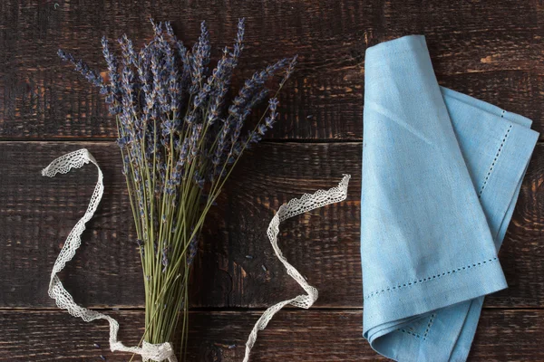 薰衣草花束和蓝色餐巾放在黑暗的木制背景 — 图库照片