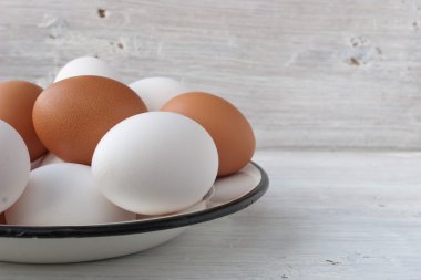 Tavuk yumurtası beyaz tahtalar üzerinde bir metal tabak