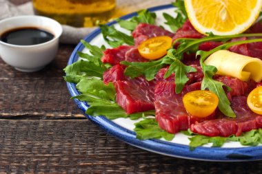 Ahşap masa üzerinde beyaz tabakta carpaccio