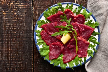 Ahşap masa üzerinde beyaz tabakta carpaccio