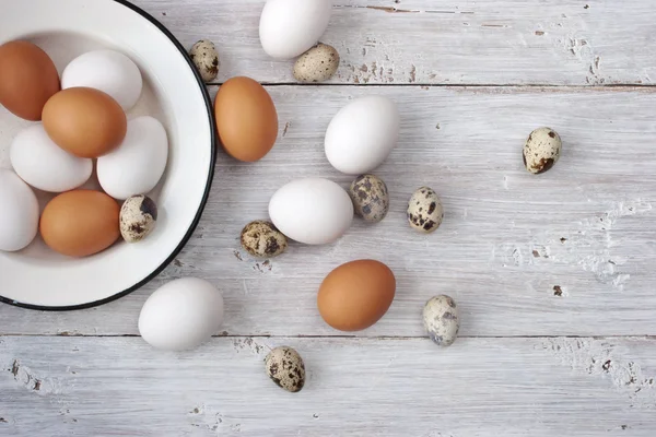 Oeufs de poulet et de caille sur la table en bois blanc — Photo