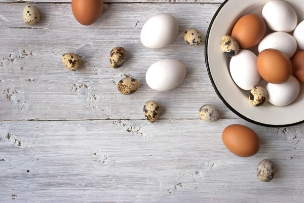 Куриные и перепелиные яйца на белом деревянном столе — стоковое фото