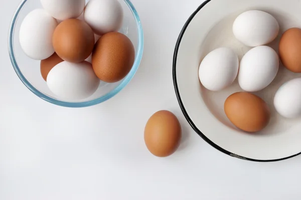 Ovos de galinha em um copo e prato de metal no fundo branco — Fotografia de Stock