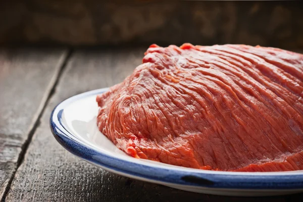 Carne rossa cruda sul piatto sul tavolo di legno — Foto Stock