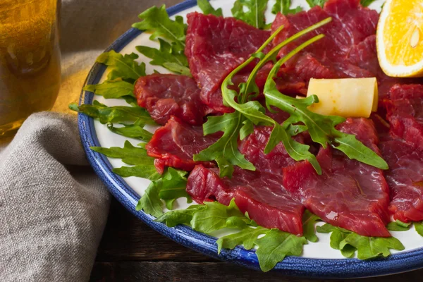 Ahşap masa üzerinde beyaz tabakta carpaccio — Stok fotoğraf