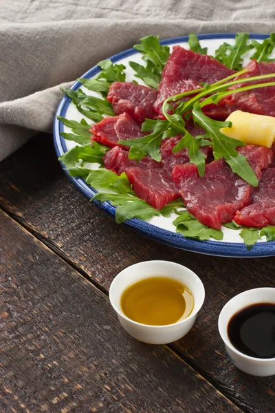 Carpaccio on the white plate on the wooden table — Stock Photo, Image