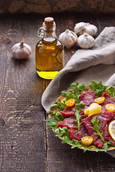 Ahşap masa üzerinde beyaz tabakta carpaccio — Stok fotoğraf