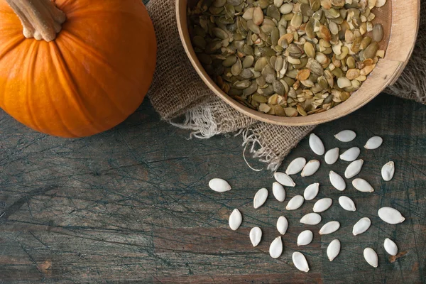 Pumpkin seeds on the rustic wooden table — Stock Photo, Image
