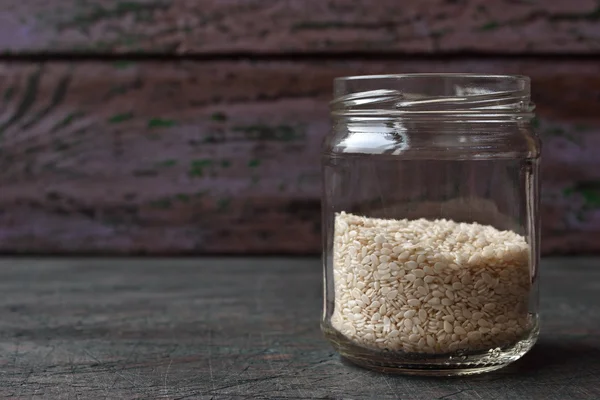 Sesame in the glass jar on the wooden table — Stock Photo, Image