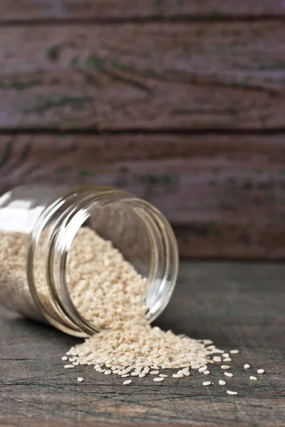 Sesame in the glass jar on the wooden table — Stock Photo, Image