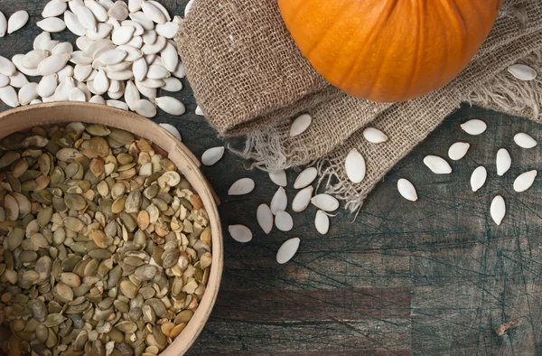 Pumpkin seeds on the rustic wooden table — Stock Photo, Image