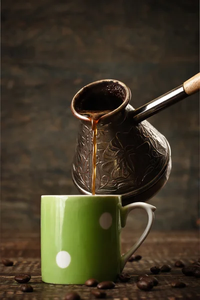 Dark coffee pours from a copper jezve into a green ceramic vinta — Stock Photo, Image