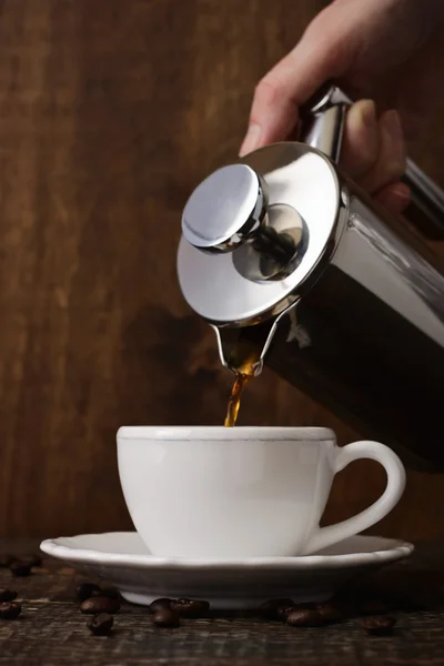 Dark coffee pours from a copper jezve into a white cup — Stock Photo, Image