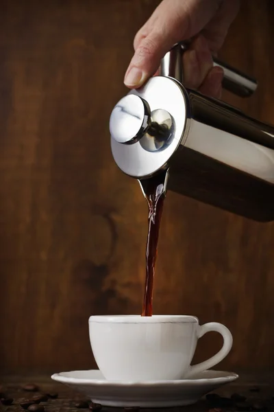 Dark coffee pours from a copper jezve into a white cup — Stock Photo, Image