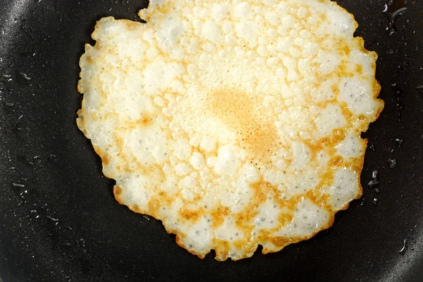 Pancake on the hot black pan — Stock Photo, Image