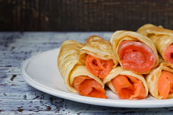 Rotoli da frittelle con salmone sul piatto di ceramica bianco — Foto Stock