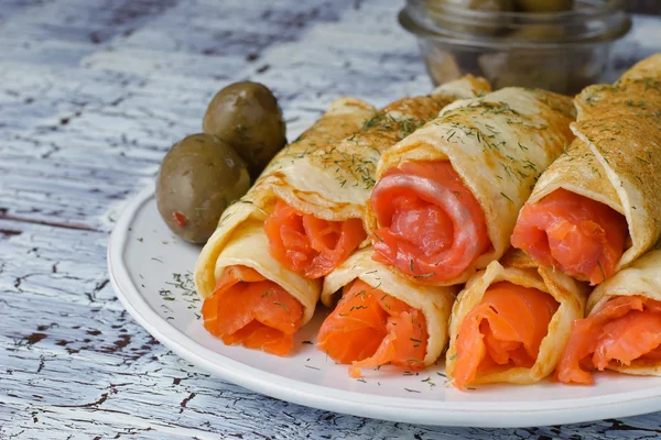 Rolls from pancakes with salmon on the white ceramic plate — Stock Photo, Image