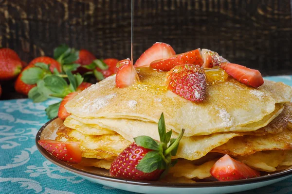 Hot pancakes with strawberries and honey on the ceramic plate — Stock Photo, Image