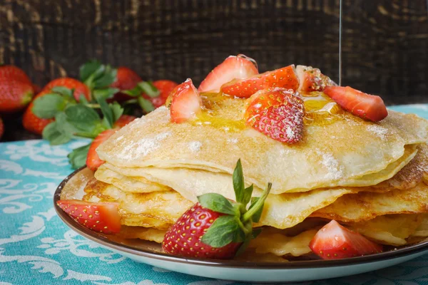 Hot pancakes with strawberries and honey on the ceramic plate — Stock Photo, Image