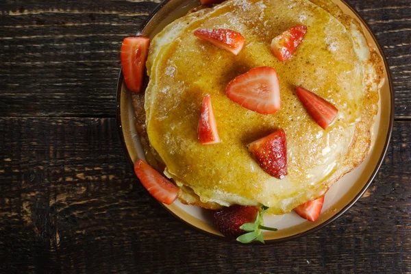 Hot pancakes with strawberries and honey on the ceramic plate — Stock Photo, Image