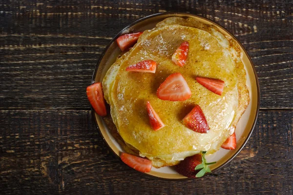 Heiße Pfannkuchen mit Erdbeeren und Honig auf dem Keramikteller — Stockfoto