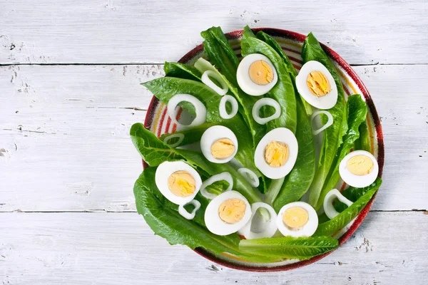 Ensalada verde con cebolla y huevos en la mesa de madera blanca — Foto de Stock