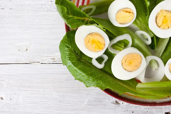 玉ねぎと卵が白い木製のテーブルの上のグリーン サラダ — ストック写真
